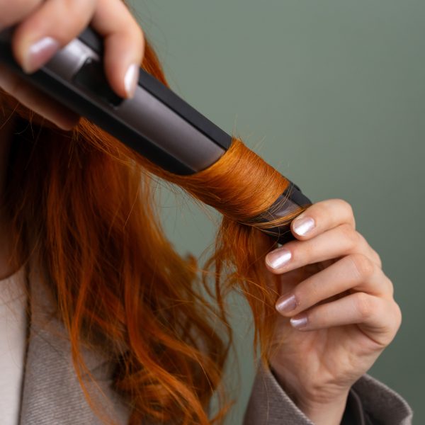 Femme ondulant ses cheveux rouges au fer