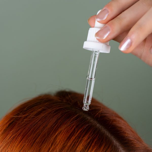 Application de sérum sur racines cheveux rouges