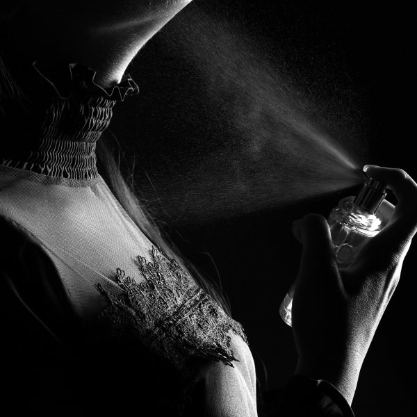 Femme pulvérise parfum en studio noir blanc