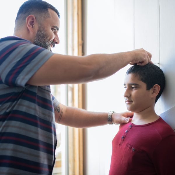 Père mesurant la taille de son fils contre un mur