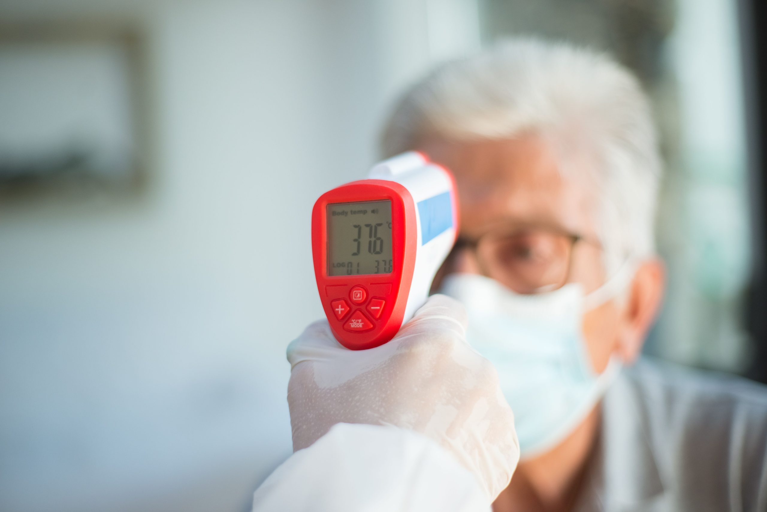 Professionnel de santé mesurant température patient senior